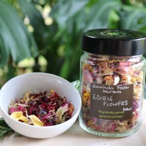 Jar of dried edible flowers with a ramekin of the flower blend beside it