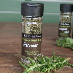 a jar of kooinda farm dried rosemary on a bench with a sprig of fresh rosemary