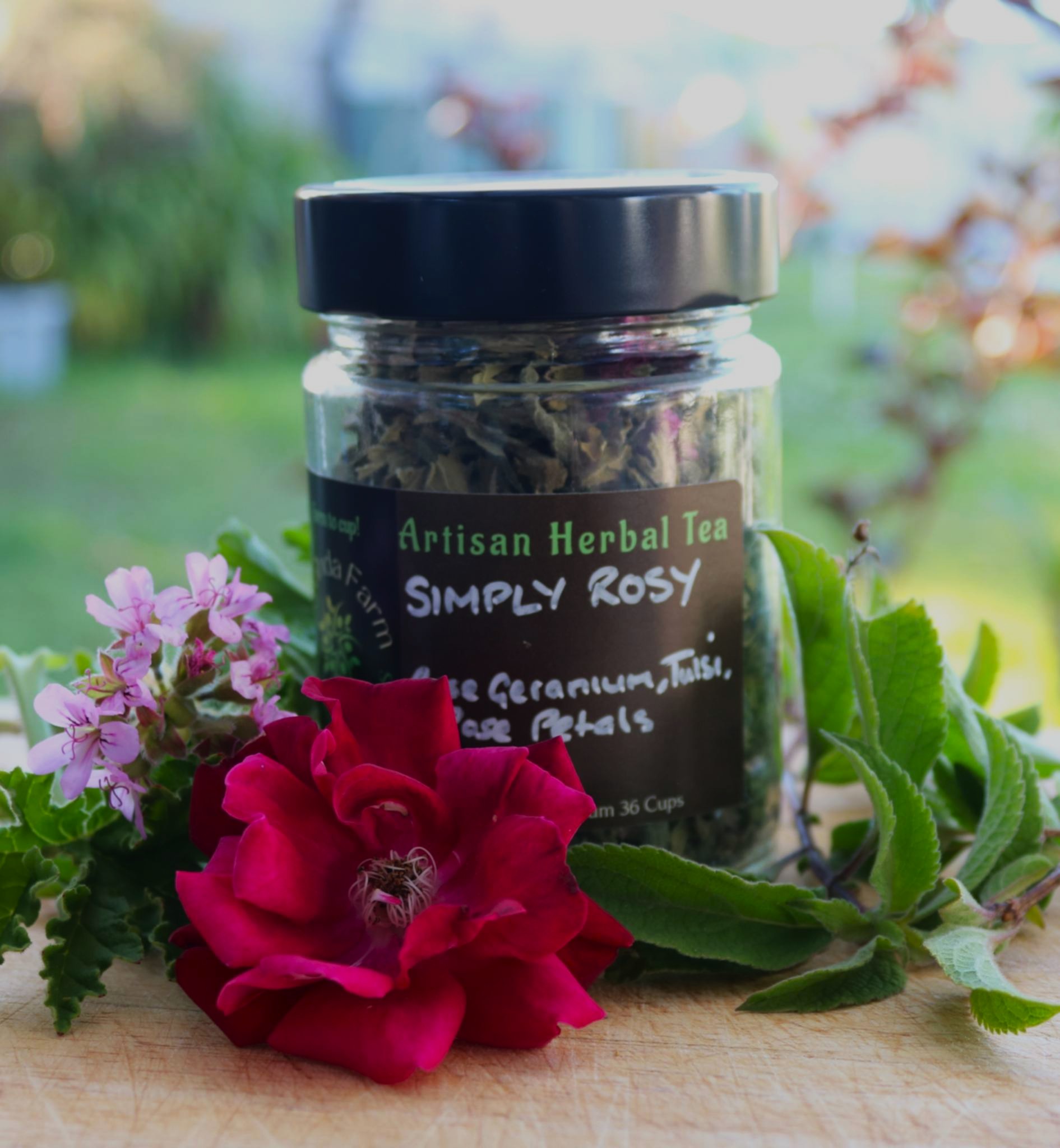 Simply Rosey jar of loose leaf herbal tea surrounded by the fresh ingredients